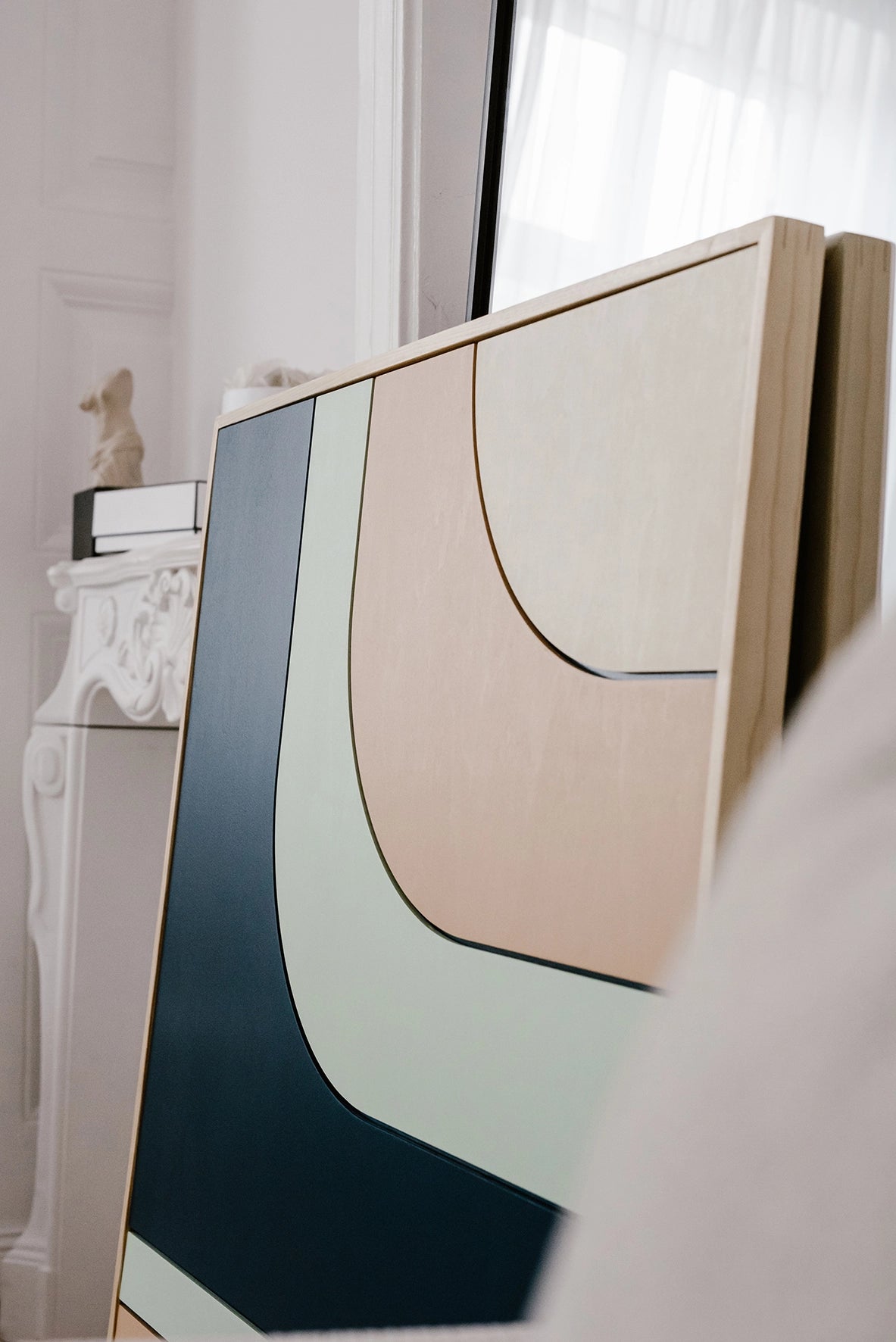 Ręcznie robiona drewniana dekoracja ścienna DEW ustawiona przy lustrze w jasnym wnętrzu.