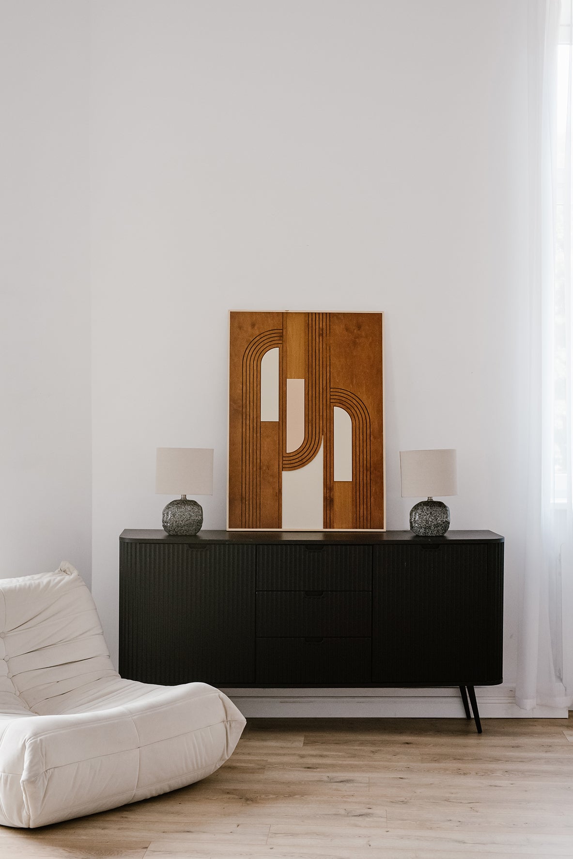 Drewniana dekoracja ścienna MODU w stylu nowoczesnym ustawiona na czarnej komodzie w jasnym wnętrzu.