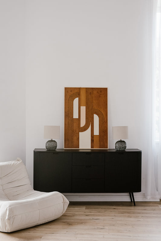 Drewniana dekoracja ścienna MODU w stylu nowoczesnym ustawiona na czarnej komodzie w jasnym wnętrzu.
